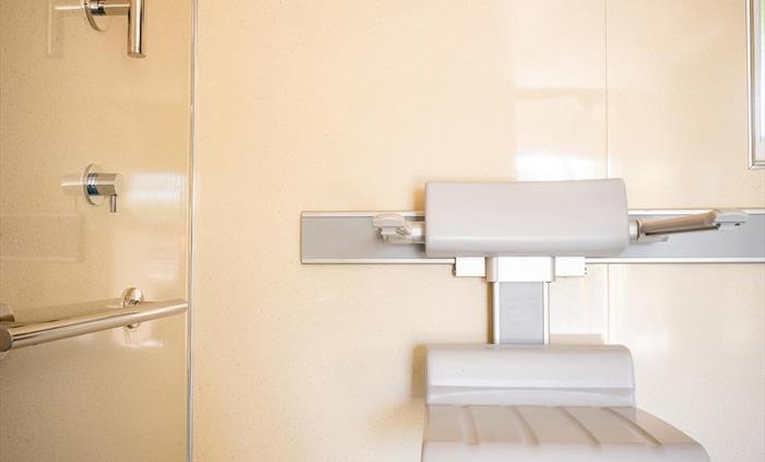 A grey shower chair shown in close up in an accessible shower